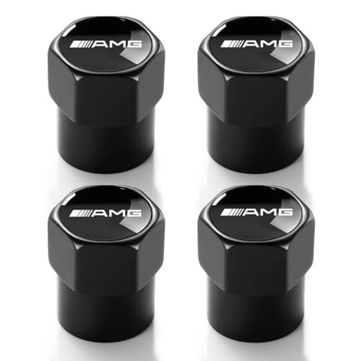 Four black metal tire valve caps with AMG logo, angled top views