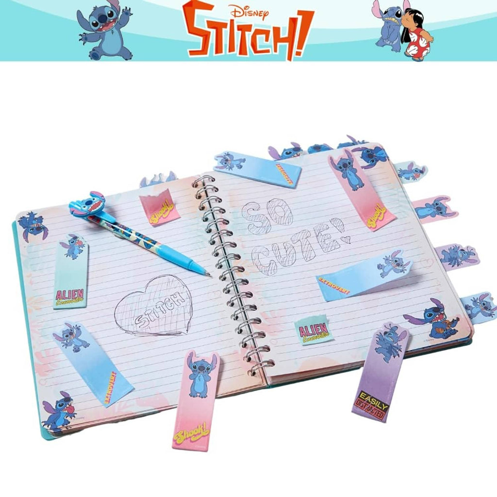 Open Stitch spiral journal with lined pages, sticky tab markers, and a blue pen.