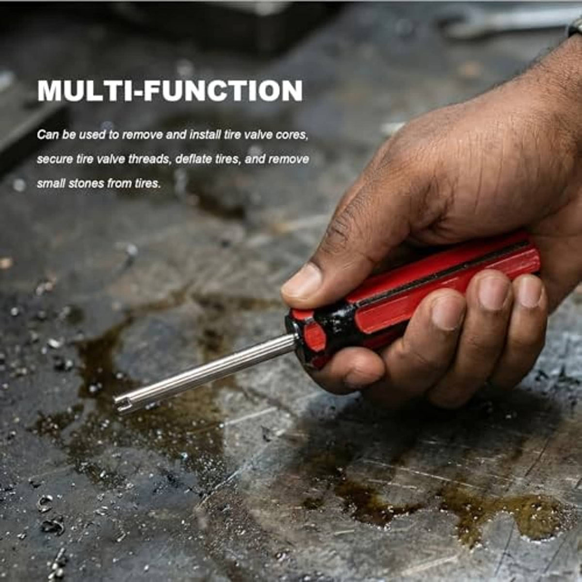 Tire valve core remover with red grip and metal shaft on a workbench surface