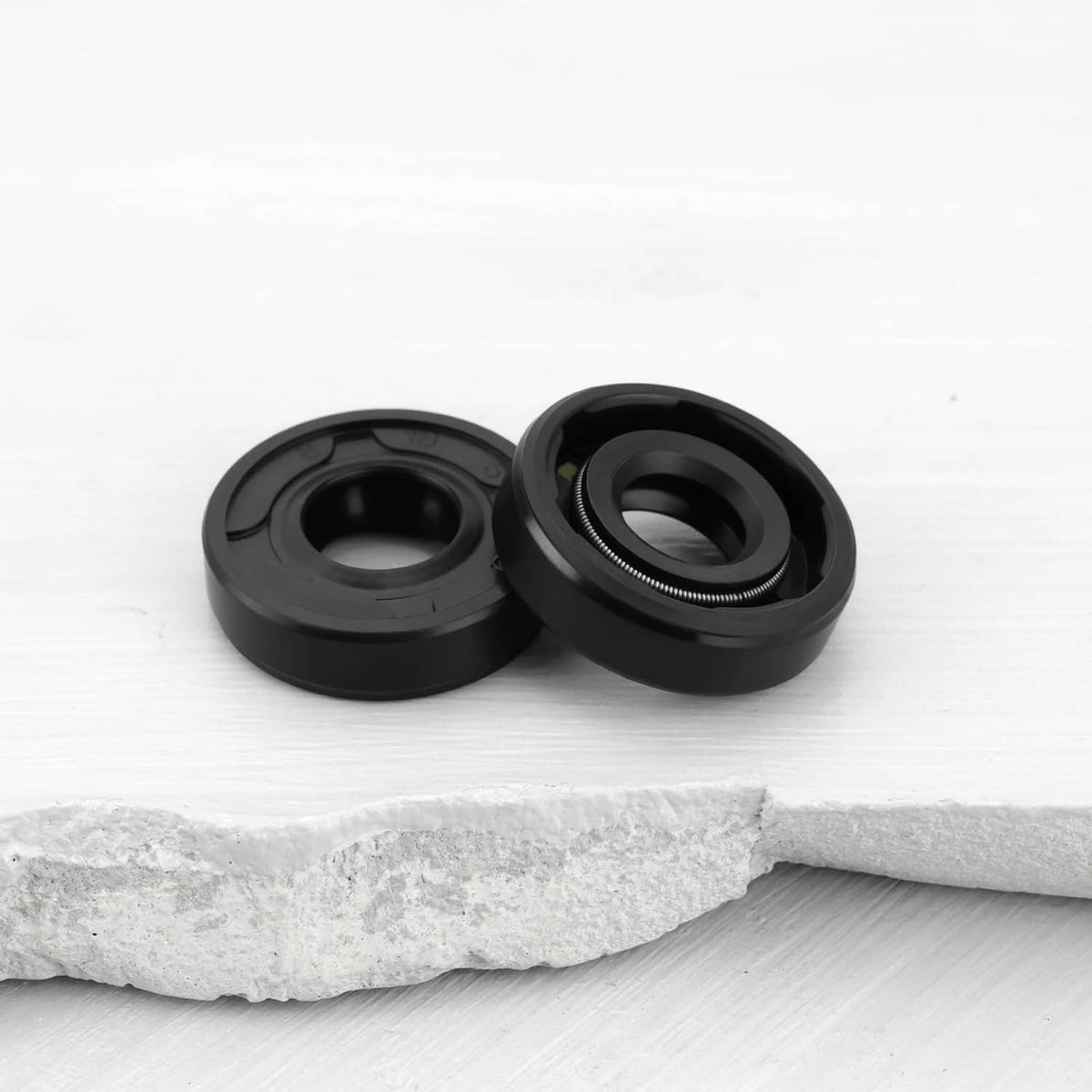 Pair of black radial shaft seals with central opening on white surface