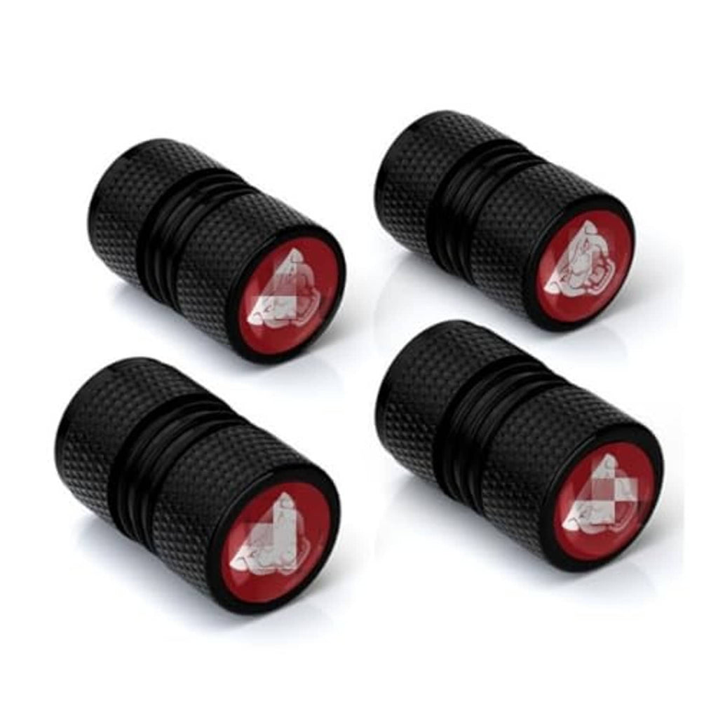 Four black textured valve stem caps with red round emblem, threaded end visible