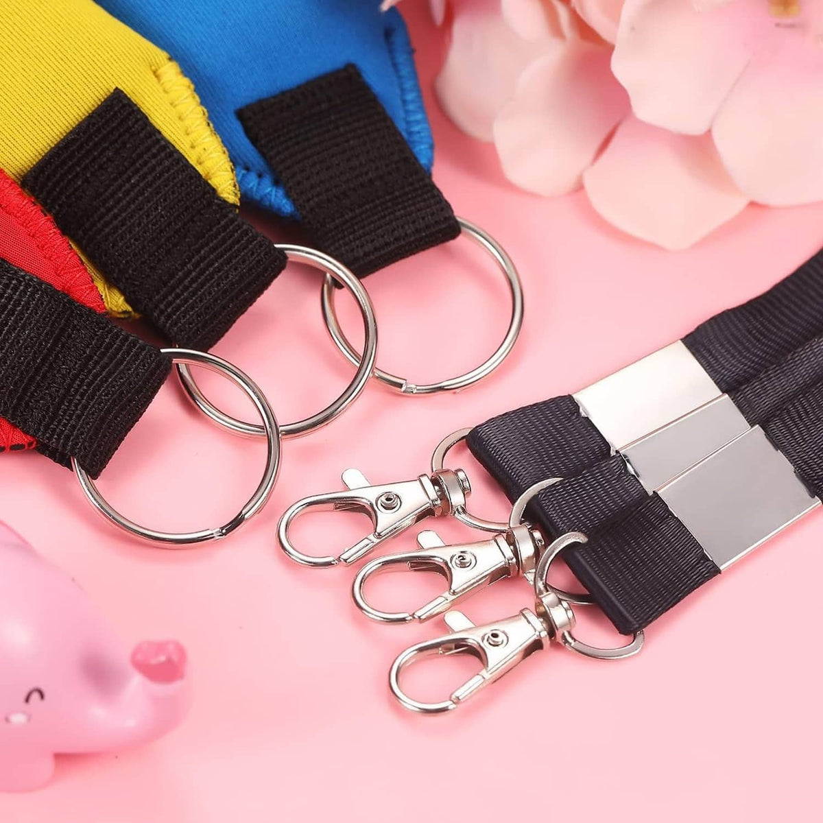 Close-up of neoprene keychain pouches with black tabs, metal rings, and key clips