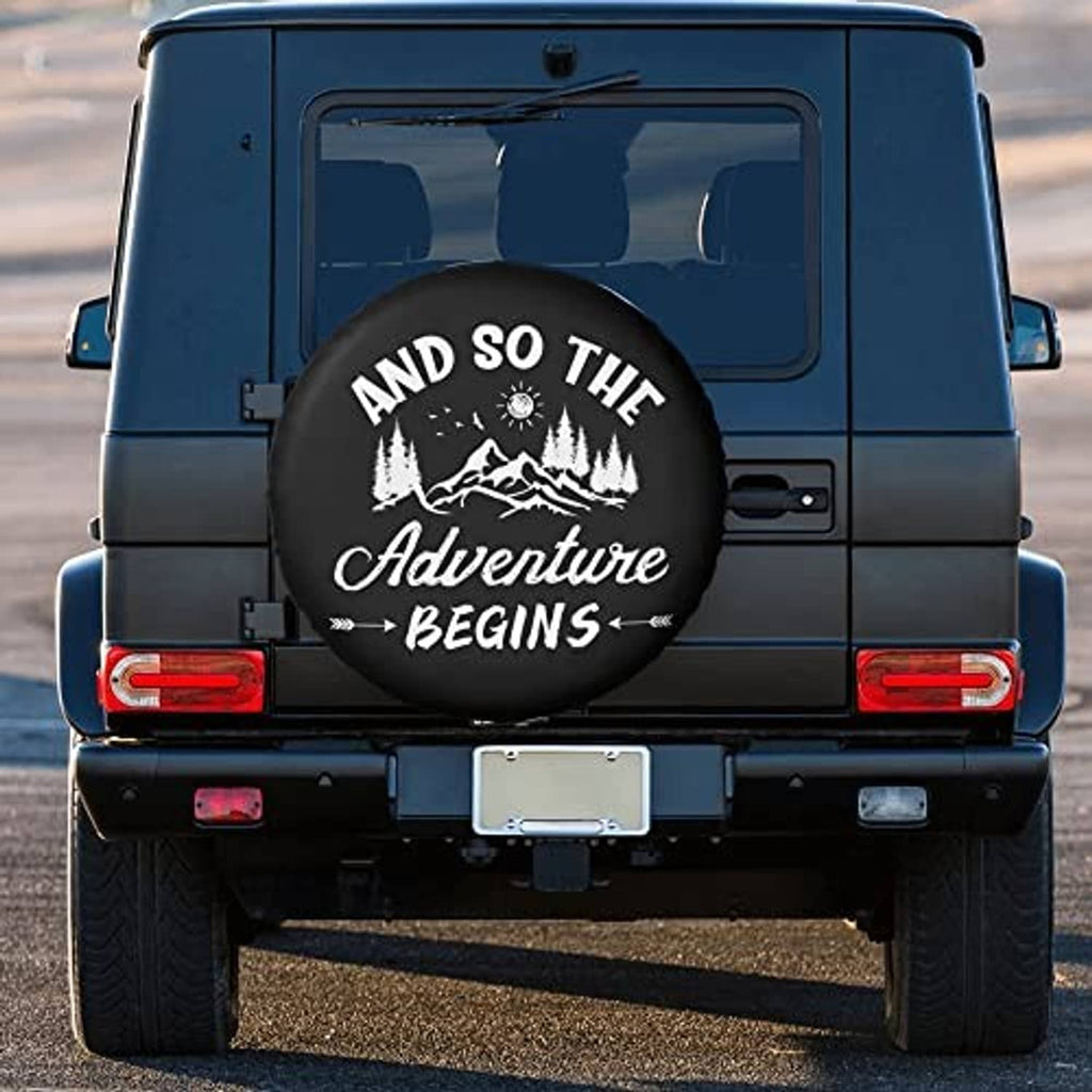 Black spare tire cover with “Adventure Begins” graphic on RV rear