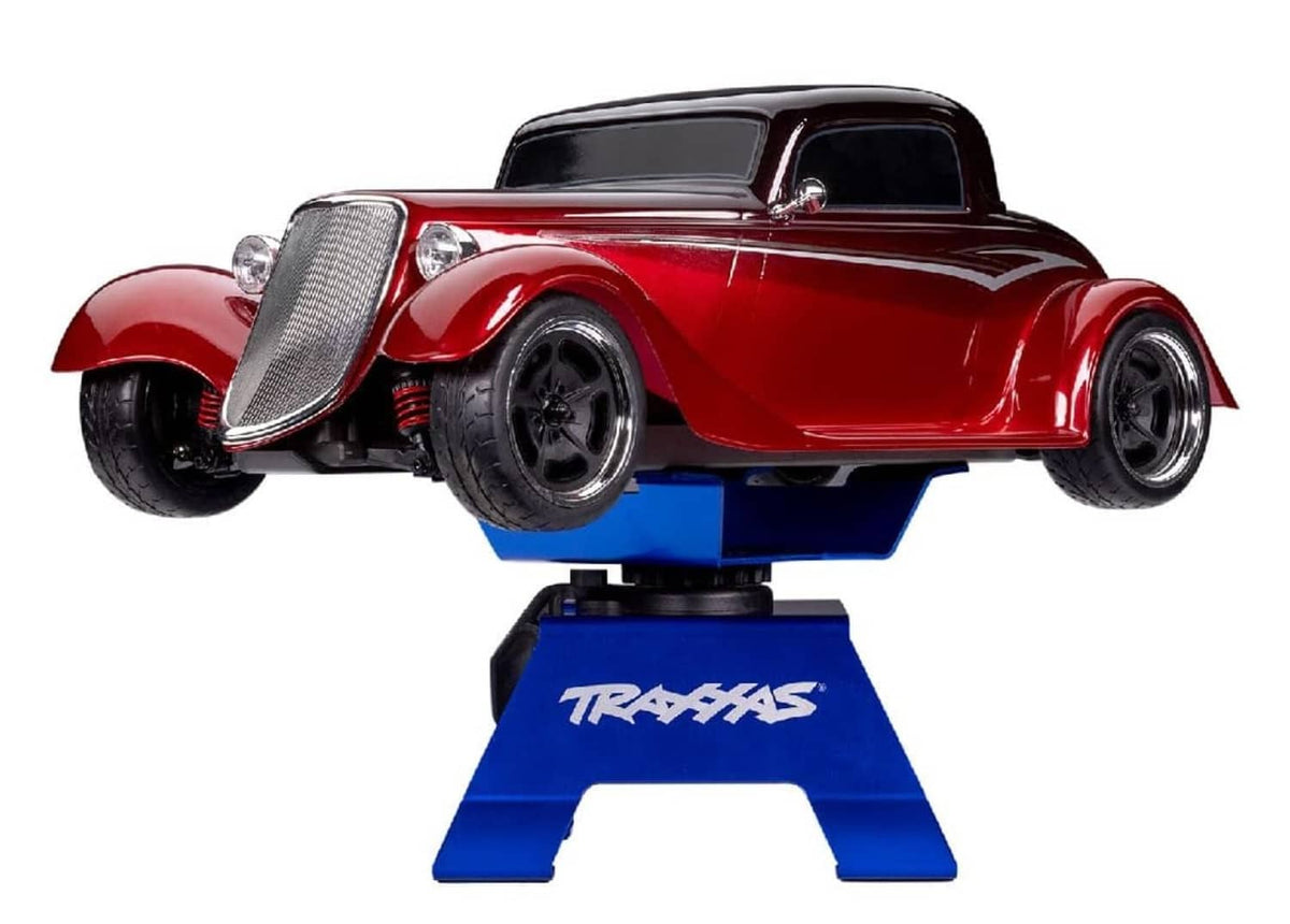 Blue TRAXXAS X-Truck stand holding a red model car