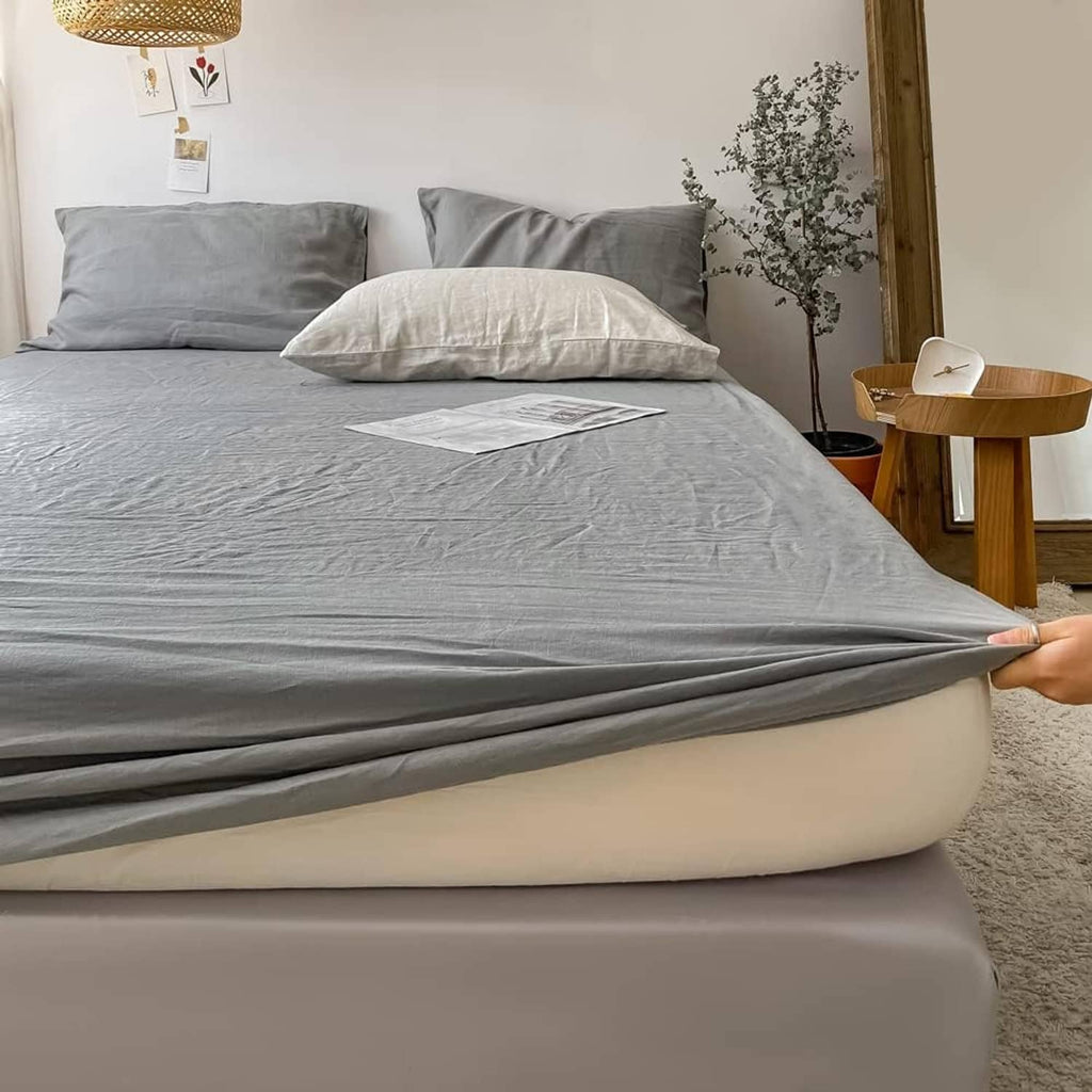 Gray linen fitted mattress cover corner detail with elastic holding the fit