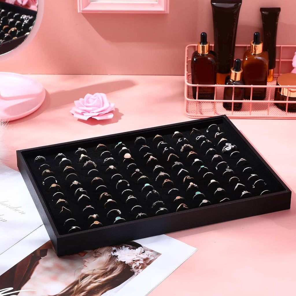 Black velvet-lined ring holder tray with 100 ring slots, on a flat surface