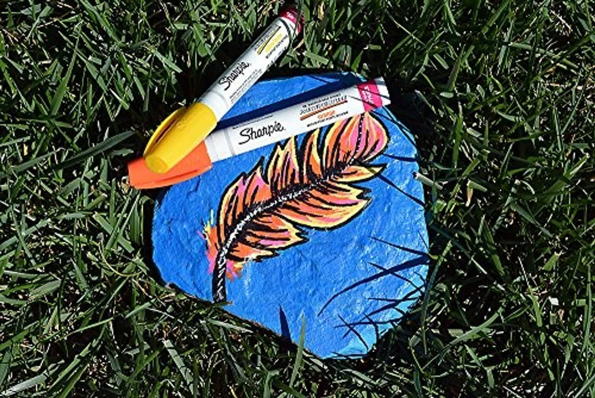Yellow Sharpie Sanford paint marker coloring a blue rock on grass