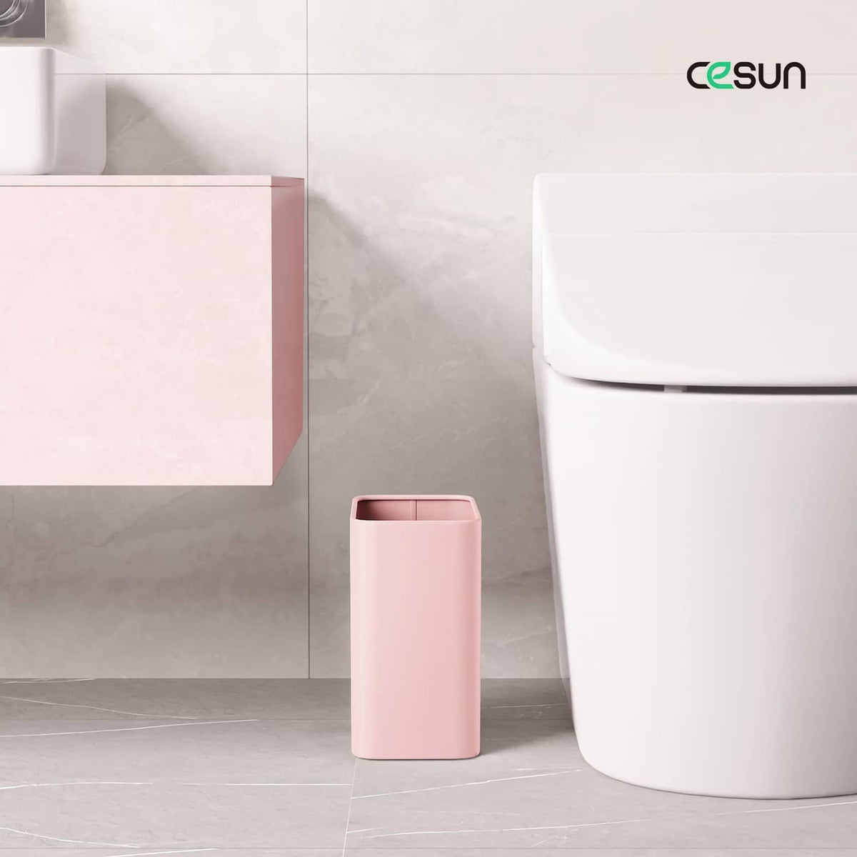 Small pink bathroom trash can standing on floor near sink and toilet