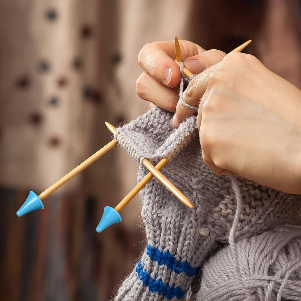 Bamboo double-pointed knitting needles in use, blue grip tips on knitted gray fabric