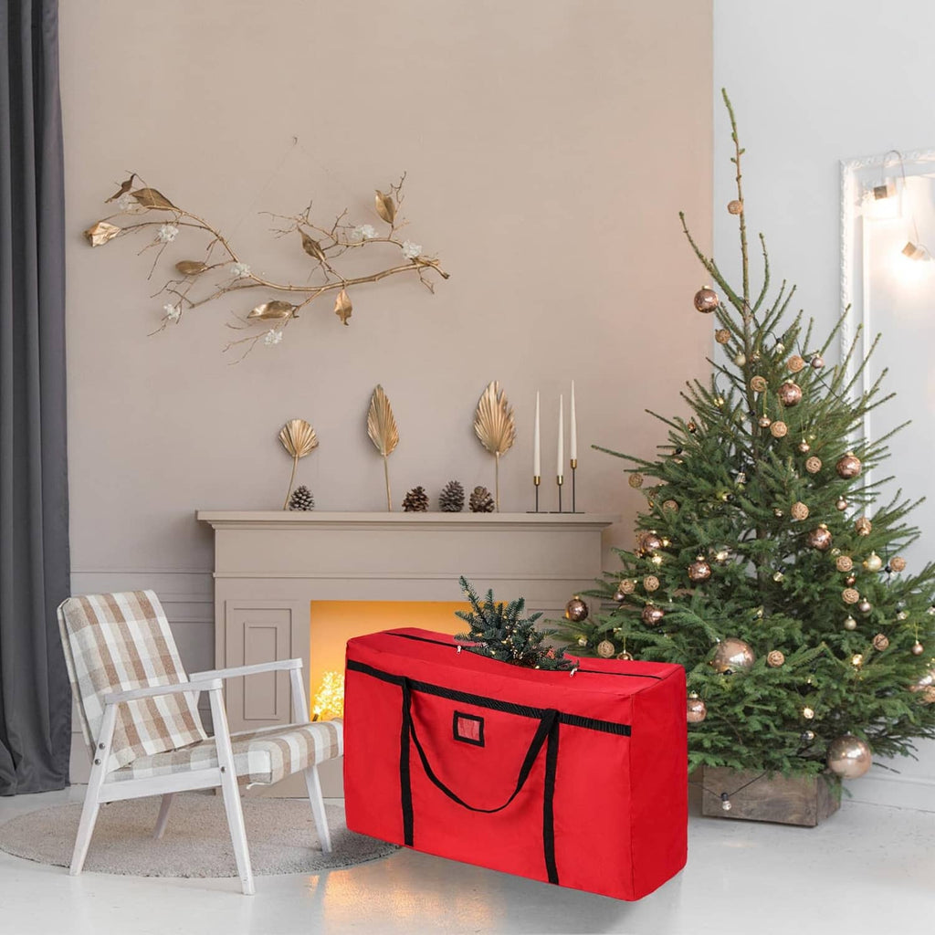 Red Christmas tree storage bag with black trim and side tote handles next to a tree.