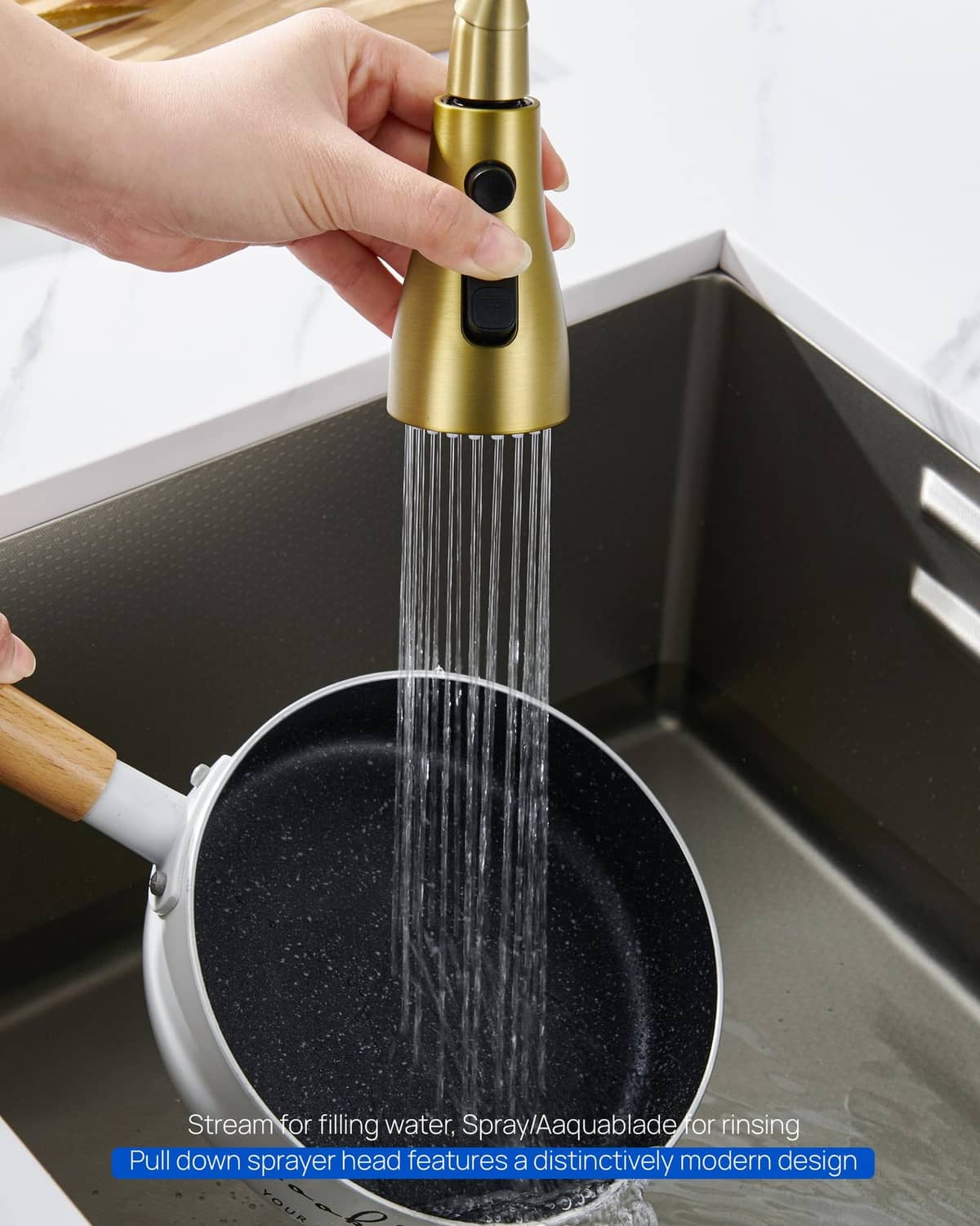 Brushed gold sprayer head held over sink with wide-spray water stream