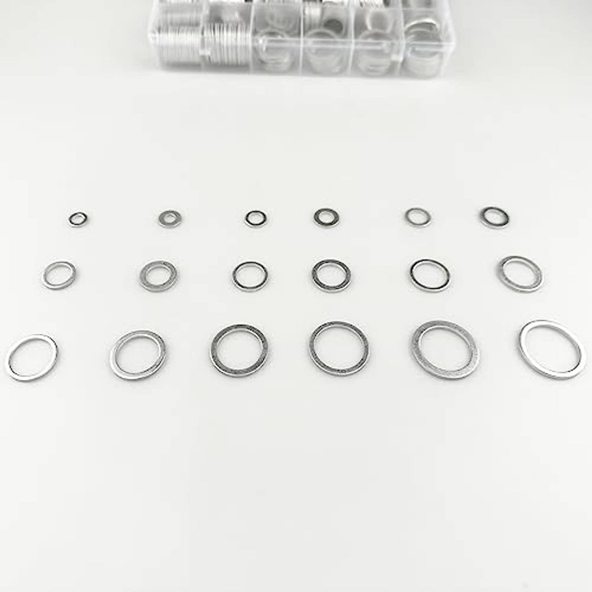 Mixed sizes of silver aluminum oil drain plug gaskets (washers) spread out for comparison