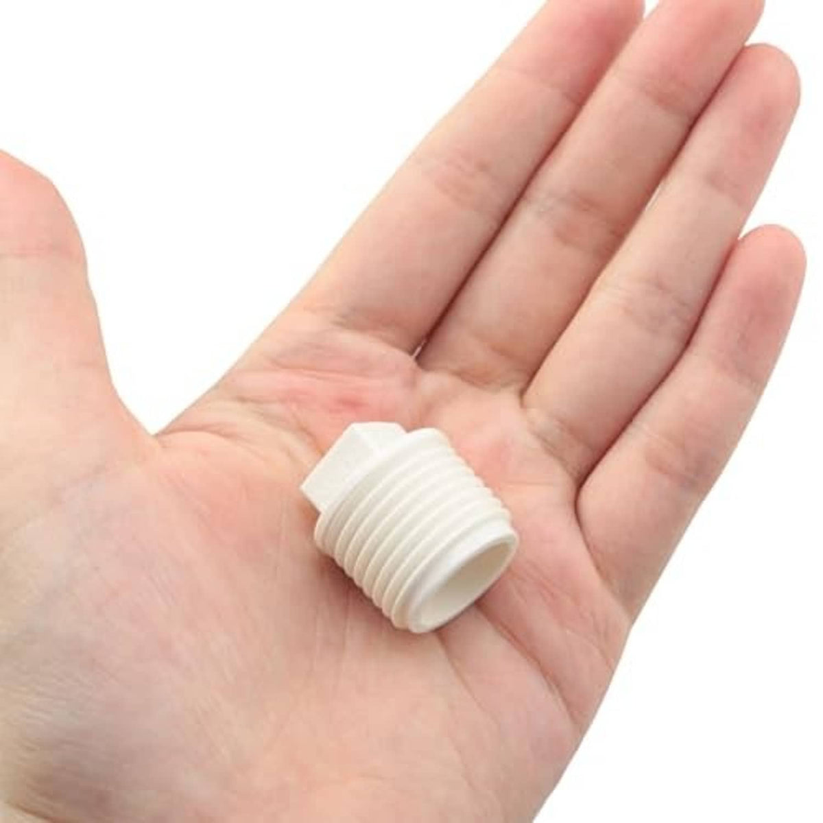 White PVC 1/2 in male thread end cap plug held in open palm