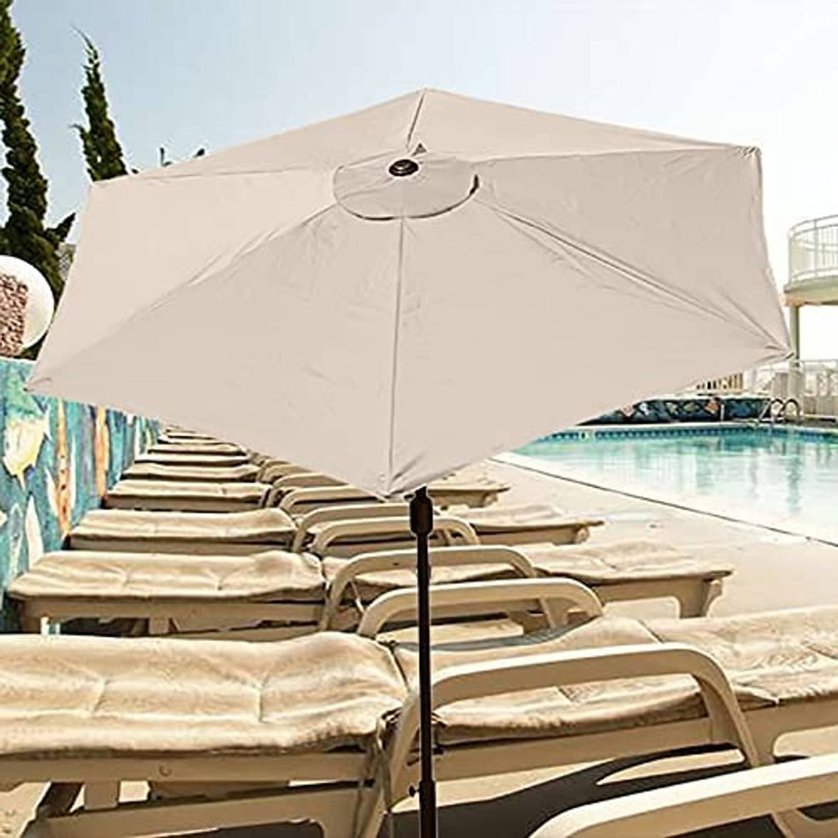 Light cream replacement umbrella canopy with center knob over poolside loungers