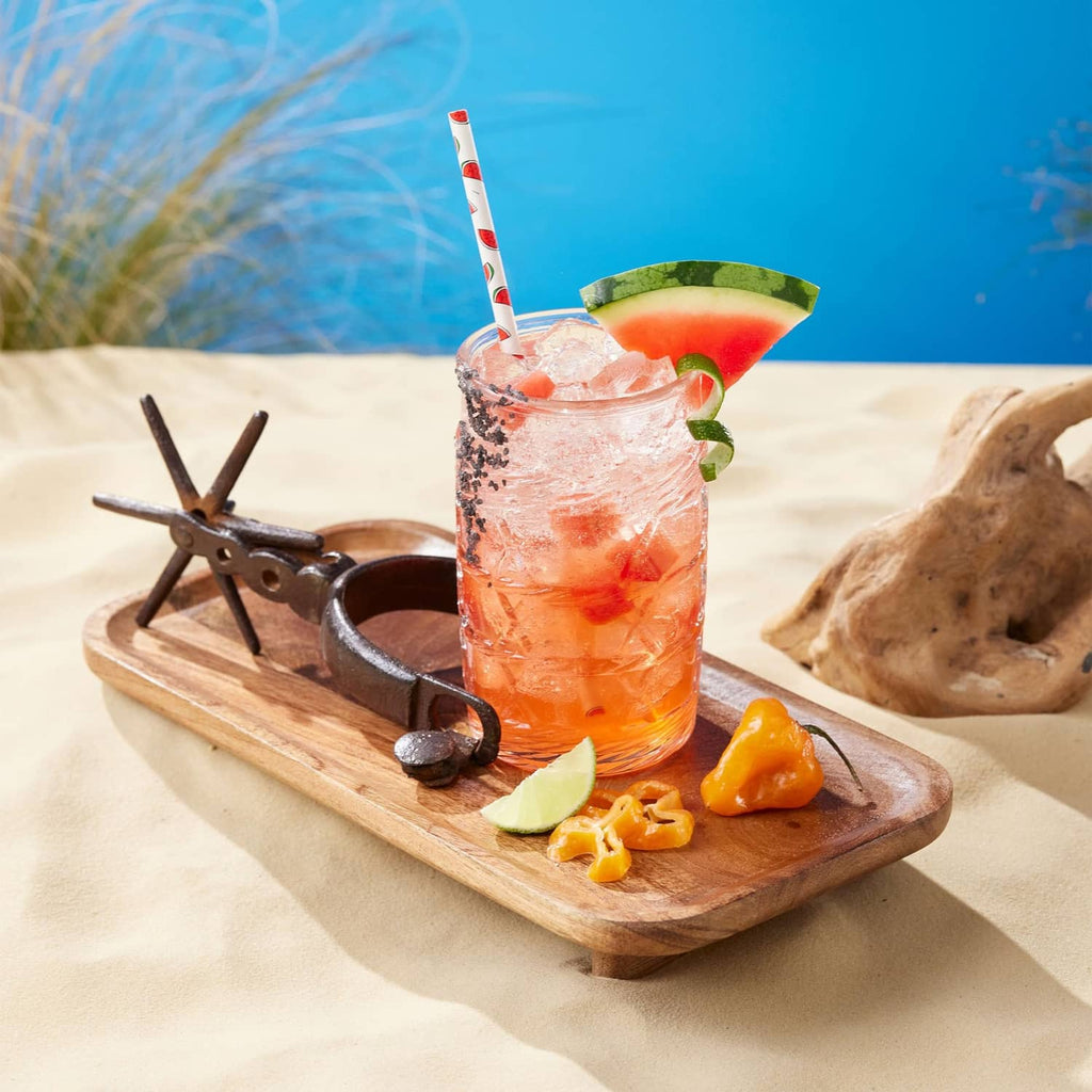 Watermelon syrup drink in a tall glass with ice, lime, and watermelon garnish