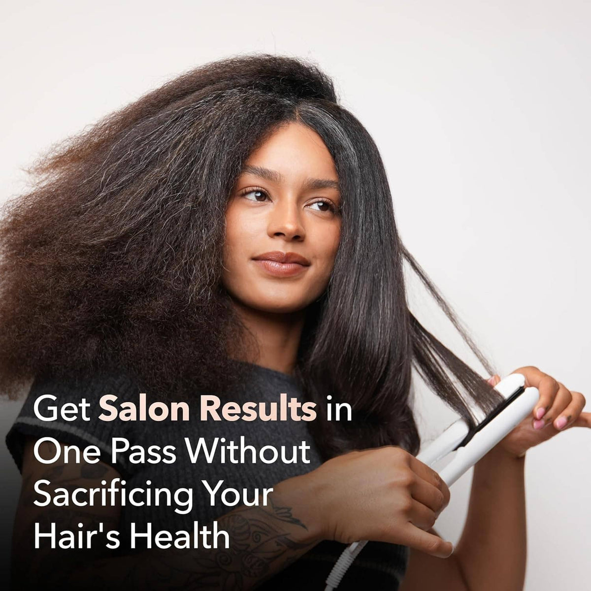 White flat iron hair straightener held near long dark hair with smoothed strands.
