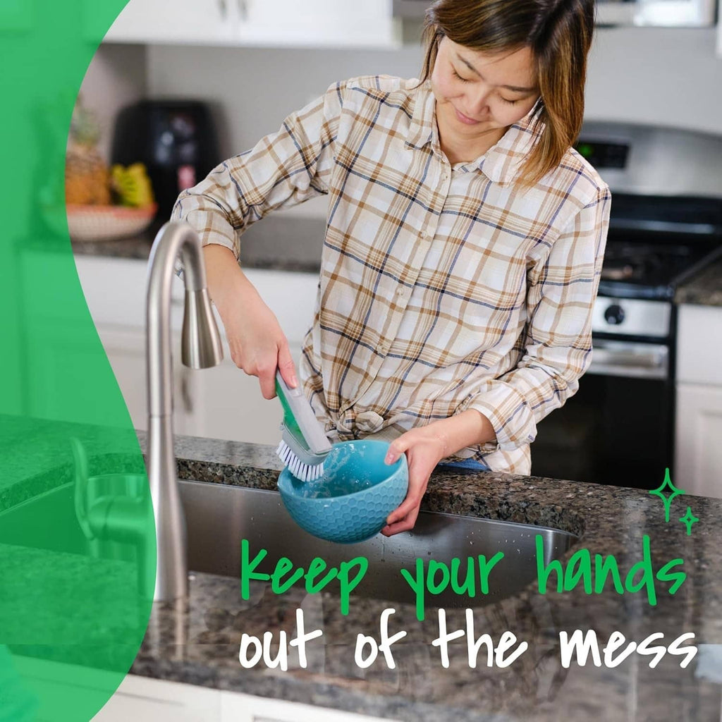 Dish brush scrubber in use, held by hand over a blue bowl