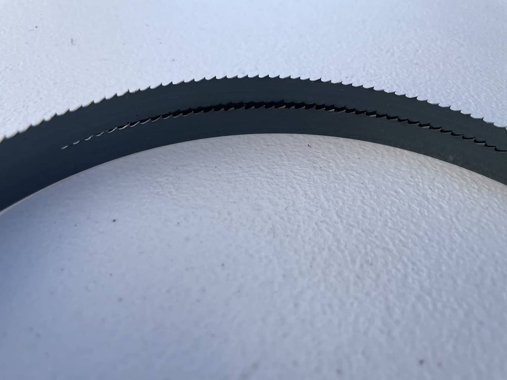 Close-up of dark blue wood bandsaw blade teeth along the band edge