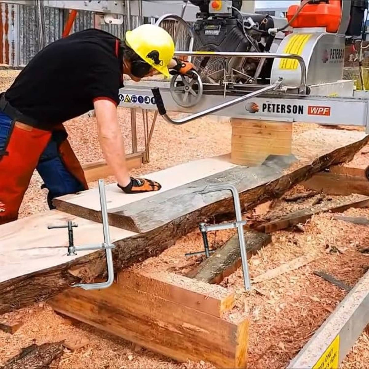 Heavy-duty U-bolt clamp securing a metal plate on a wooden work surface