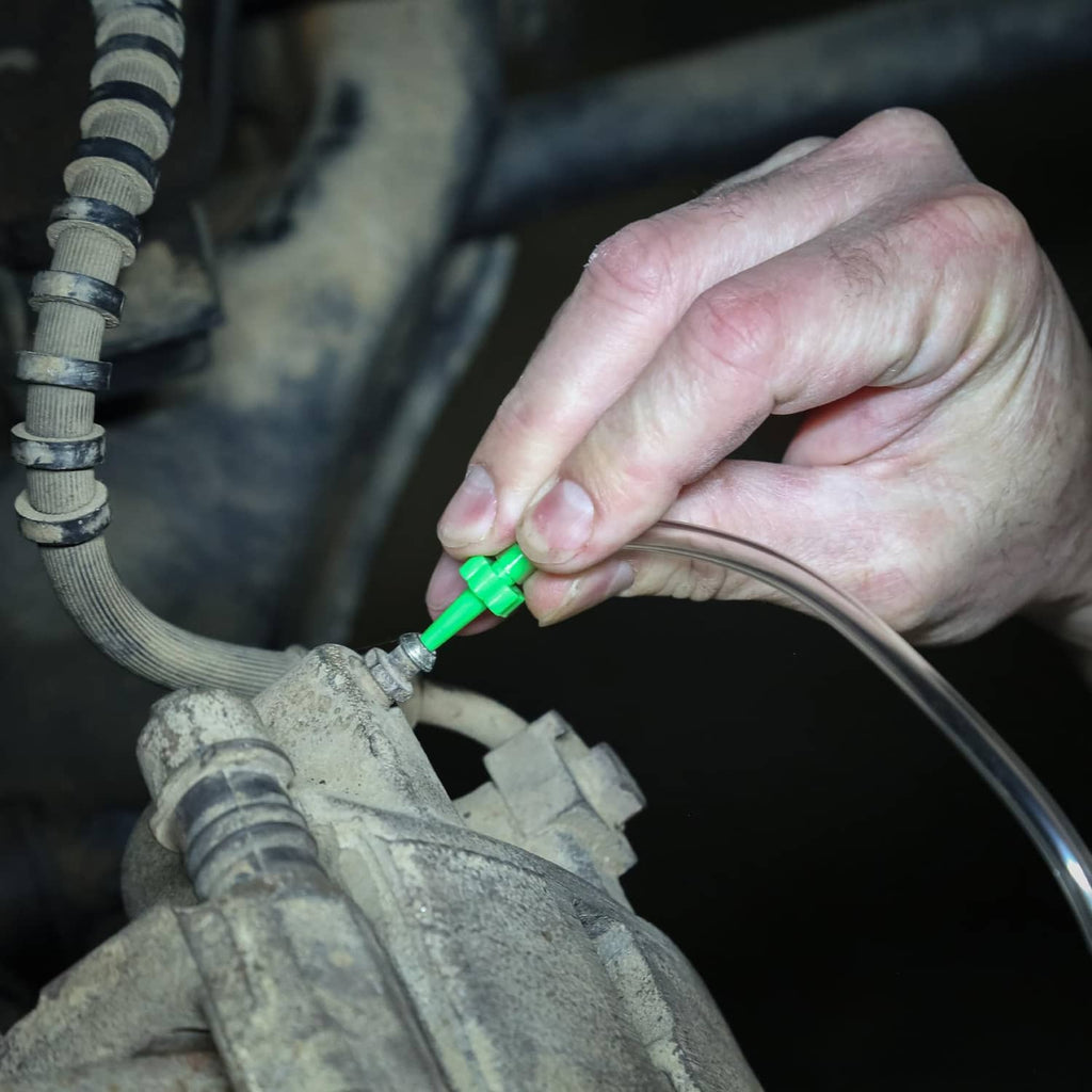 Green brake bleeder fitting connected to a vehicle brake line with clear hose