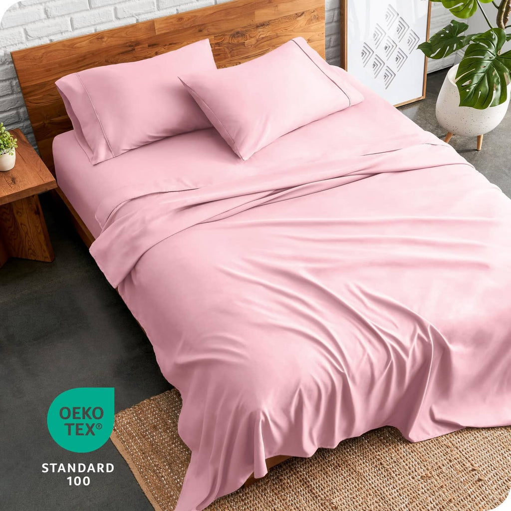 Light pink bed linen set with pillowcases and flat sheet draped over a full-size bed
