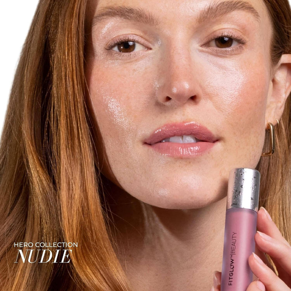 Nude rose lip gloss serum on lips with silver-capped tube held near mouth