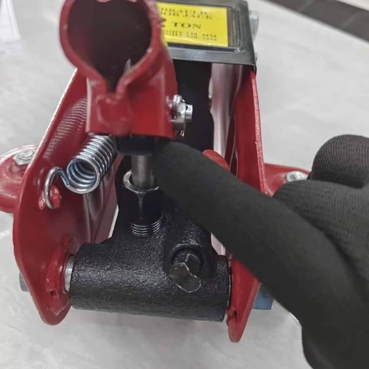 Black clamp clip on a floor jack arm with spring and metal pin