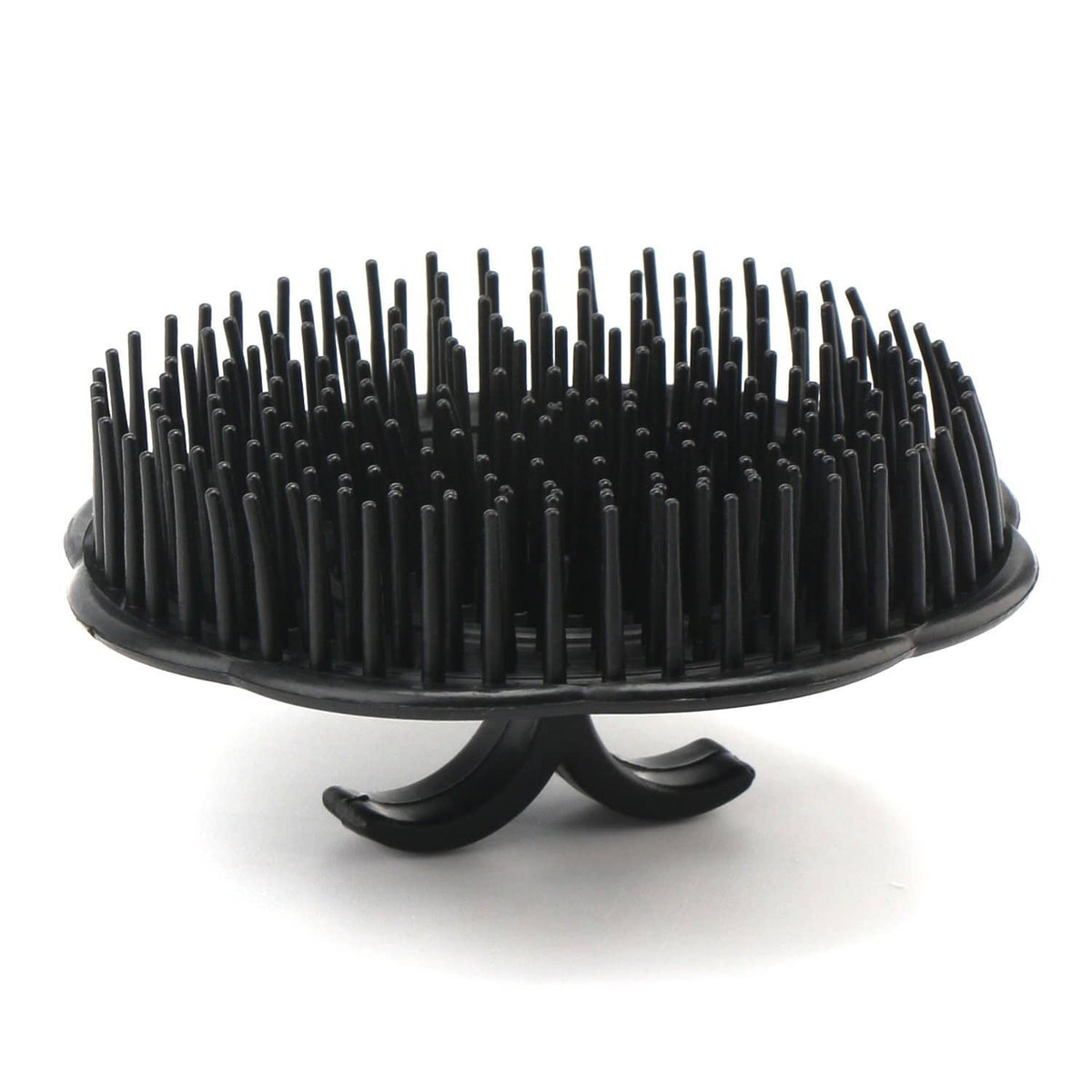 Black scalp massage brush with dense bristles on an oval pad and curved stand