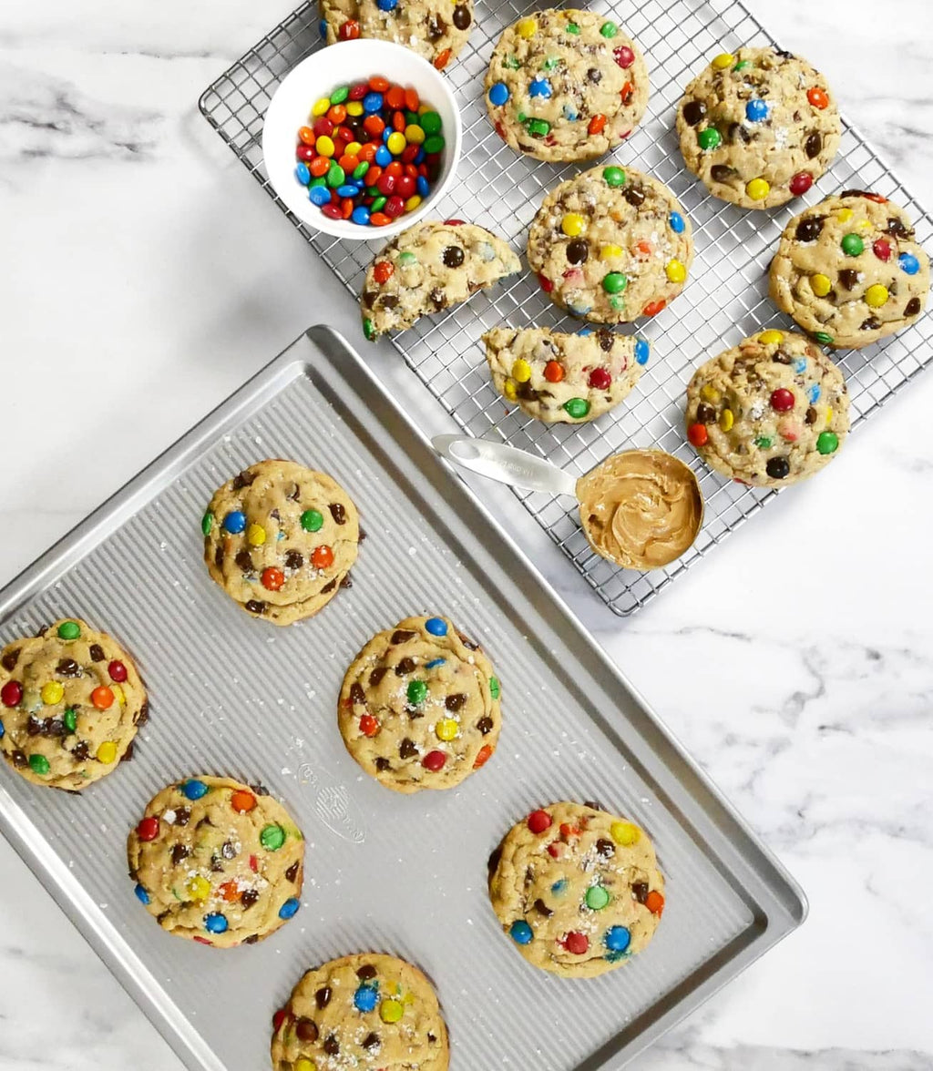 Large cookie sheet with baked sprinkle cookies and a few cookies on another tray