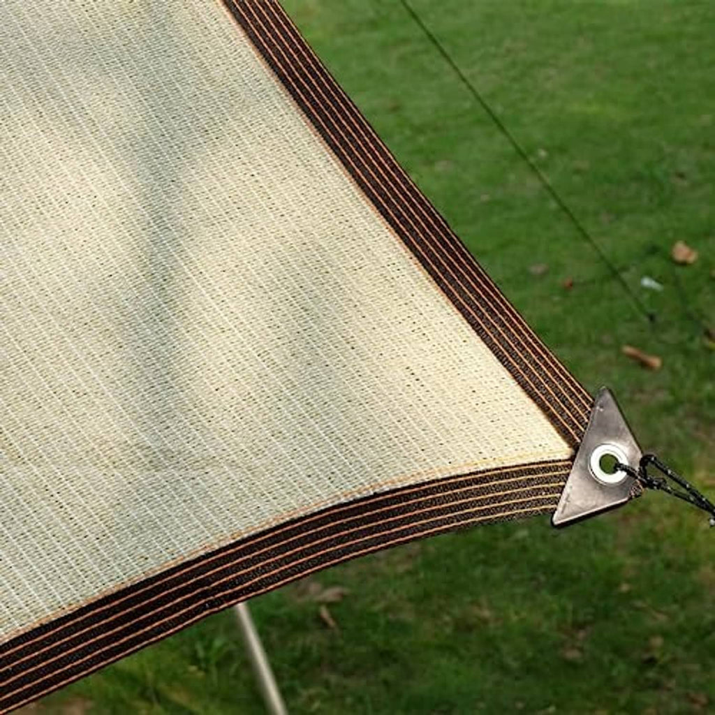 Beige outdoor sunshade cloth with dark striped border and corner fastening on grass