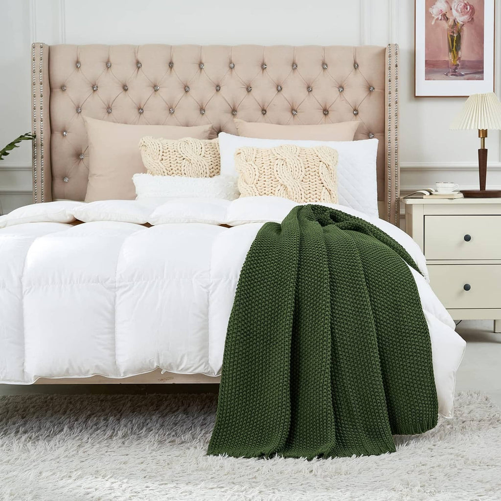Olive green cable knit throw blanket draped over a bed edge