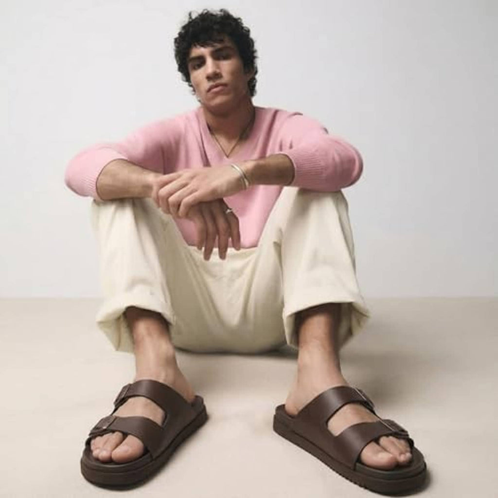 Men's brown slide sandals with adjustable buckles, worn with light shorts