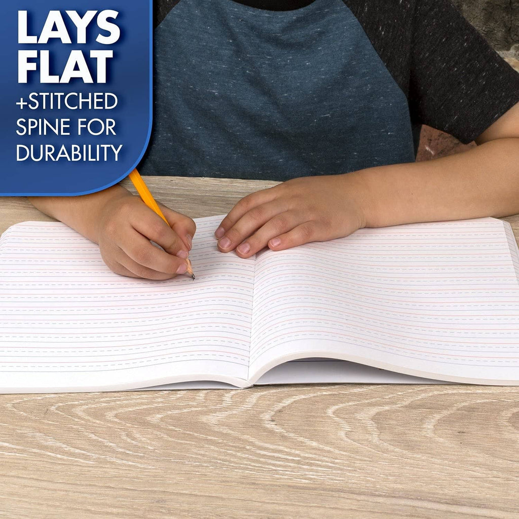 Hands writing in an open primary composition notebook with lined pages on a desk