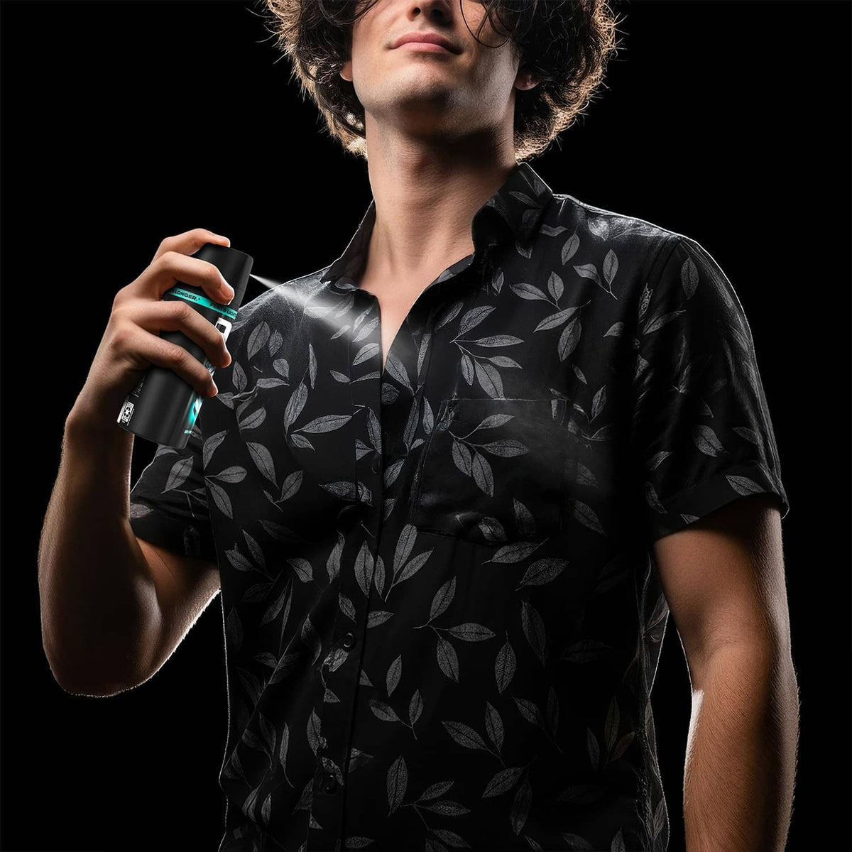 Man wearing dark patterned shirt holding an AXE deodorant body spray can