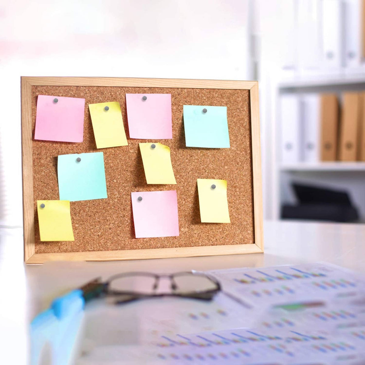 Sticky notes pinned on corkboard with gray round-head thumbtacks and gold pins