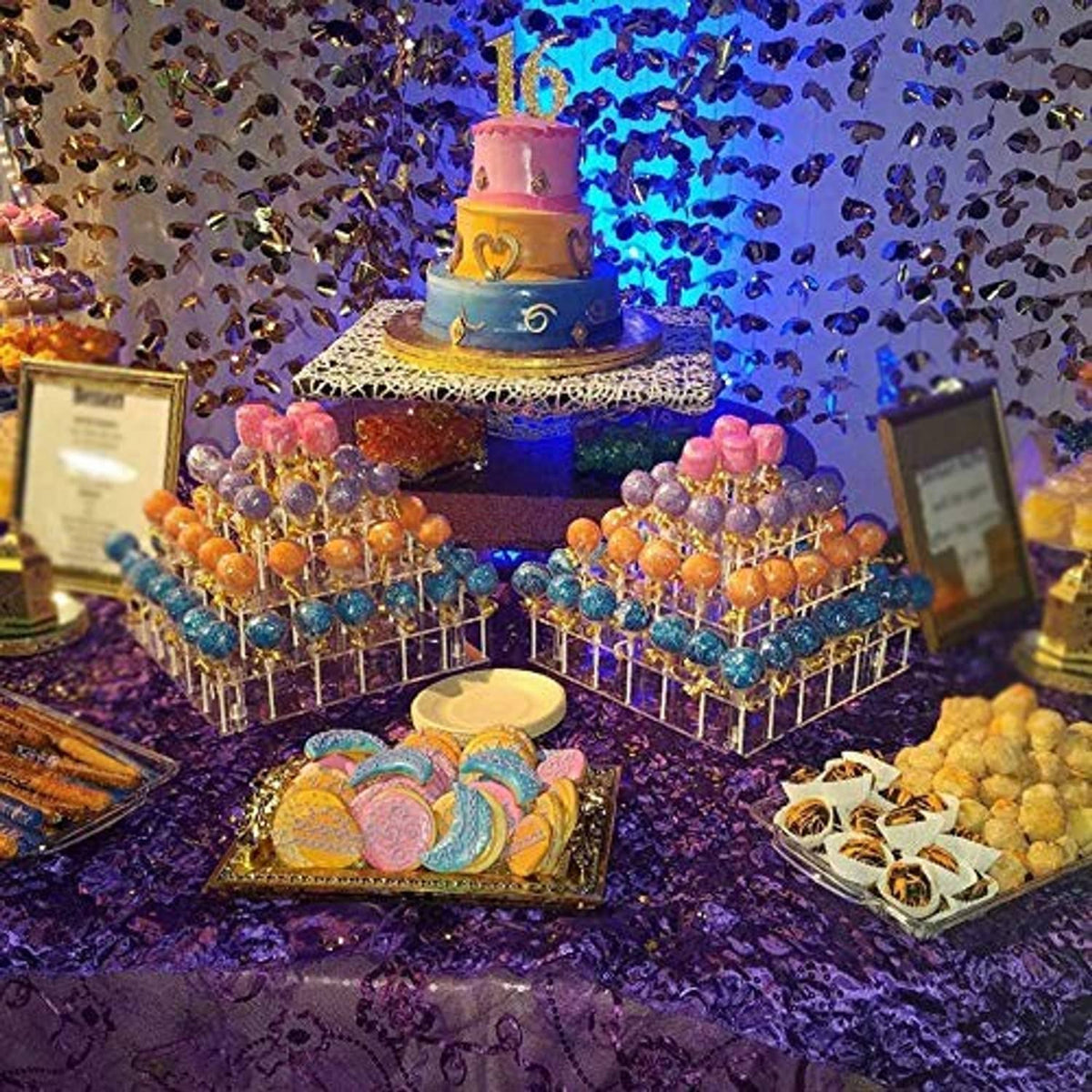 Clear three-tier cake pop stand at a dessert table holding decorated cake pops