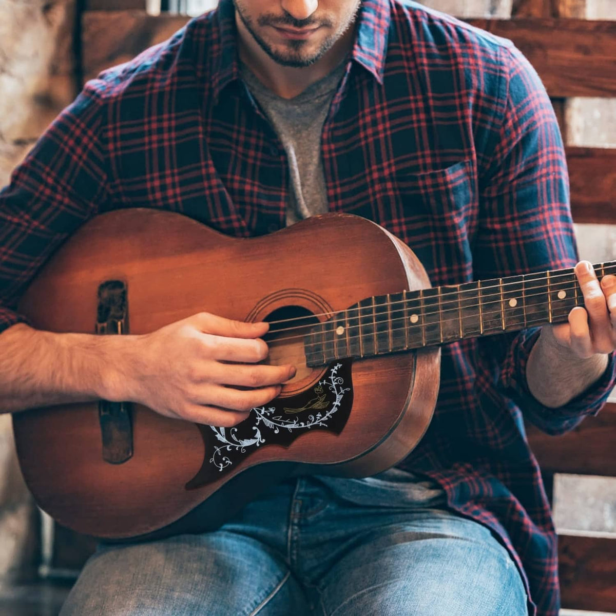 Acoustic guitar showing installed black pickguard with white decorative pattern