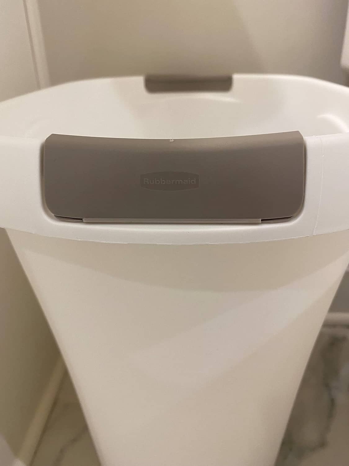 Gray swing lid on a white Rubbermaid open-top trash can