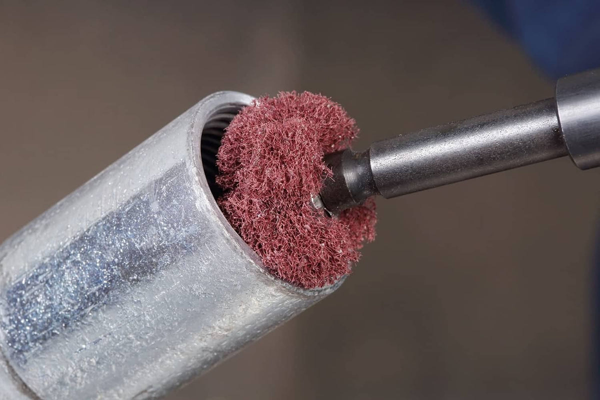 Cone-shaped abrasive buff head with pink/red textured surface on metal shank