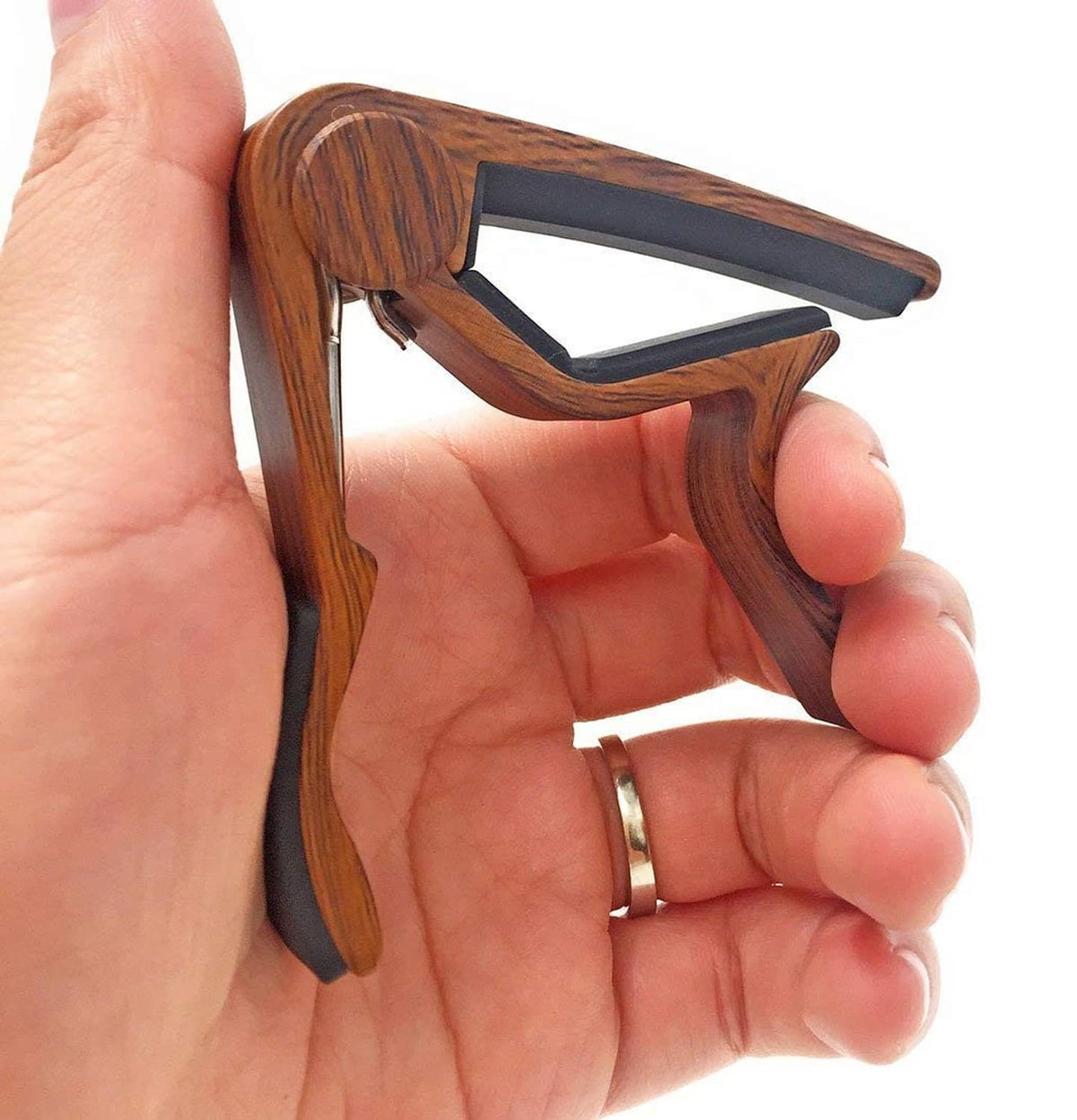 Rosewood woodgrain guitar capo held in hand with black clamp pads