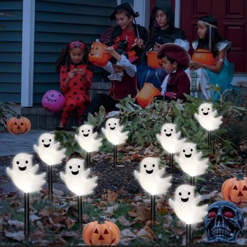 Glowing white ghost solar path lights with smiling faces on outdoor walkway