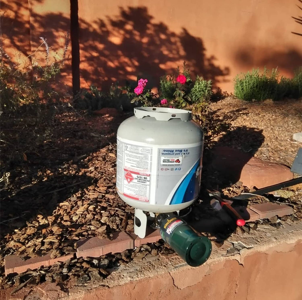 LP gas refill adapter connected to a propane cylinder valve with brass and black parts