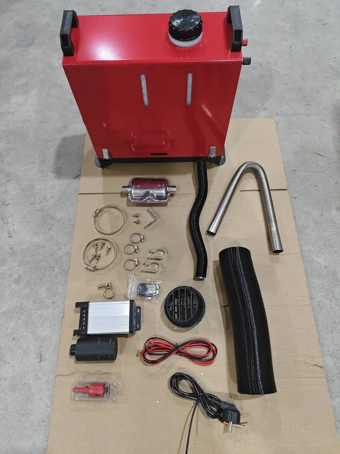 Red diesel air heater with installation parts kit and duct hose on surface