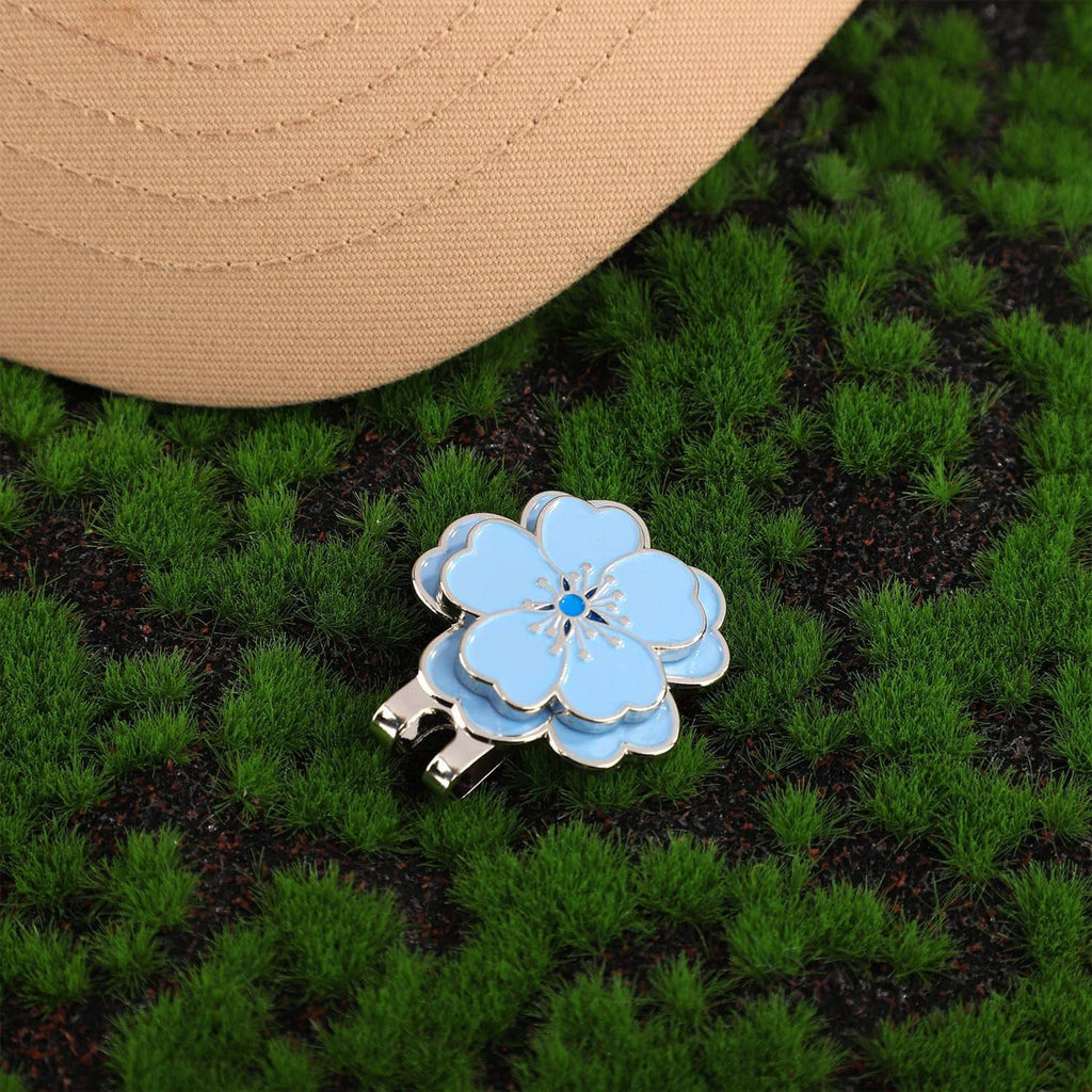 Blue flower magnetic golf ball marker with silver clip on green artificial turf