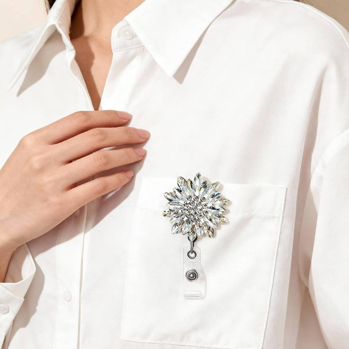 Crystal flower badge reel clipped to a white shirt pocket with retractable cord