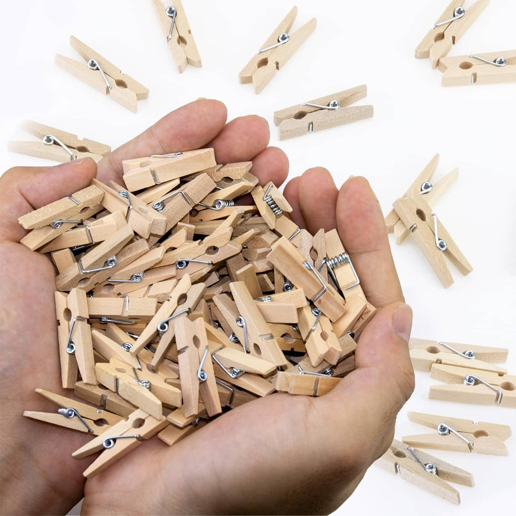 Hand holding wooden mini photo clothes pins set with metal spring clips