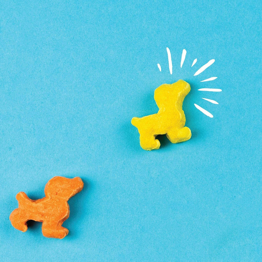 Puffed dog treats in yellow and orange dog shapes on blue background