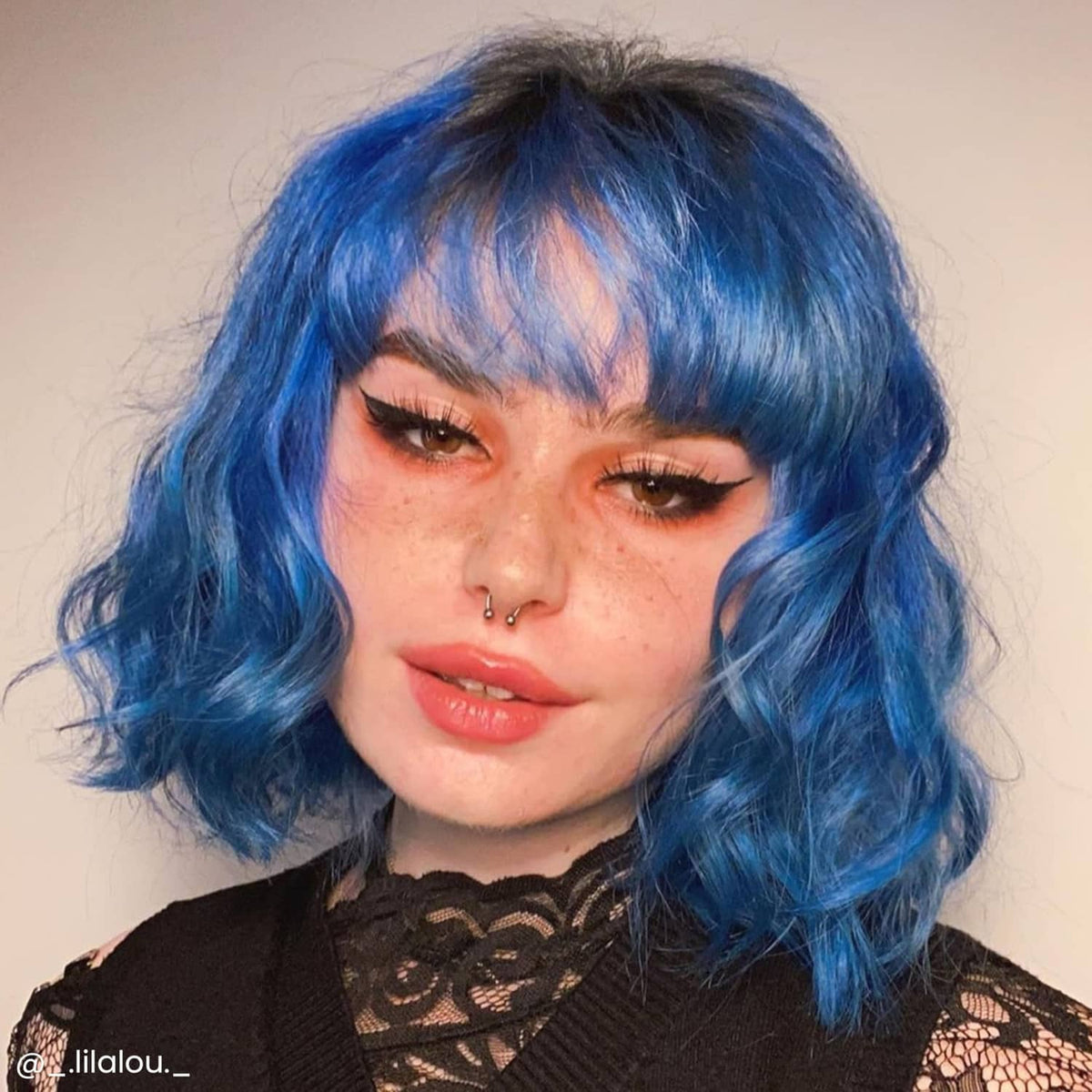 Shoulder-length wavy hair dyed Poseidon blue with straight bangs and center part.