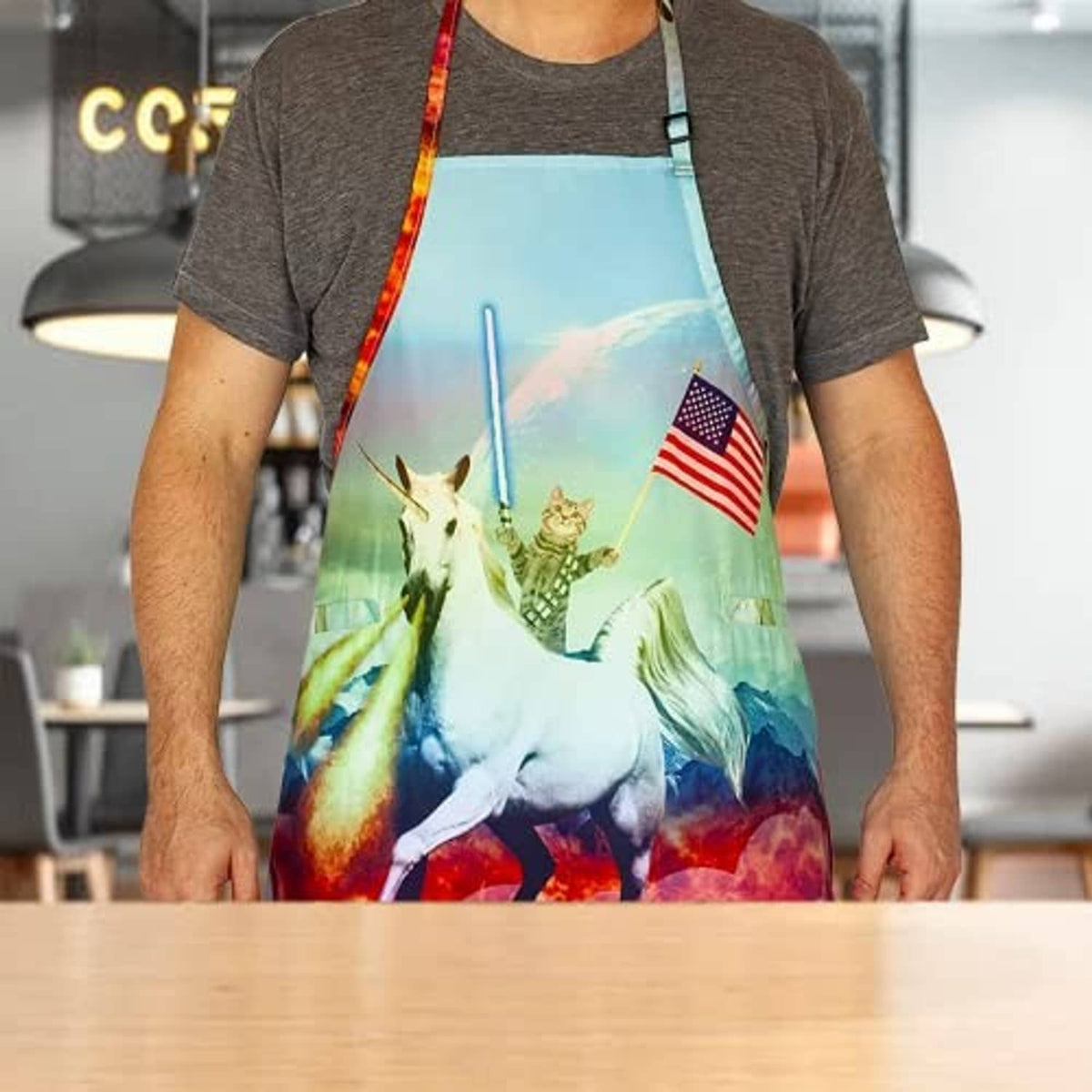 Unicorn print apron with adjustable neck strap and red trim, front view