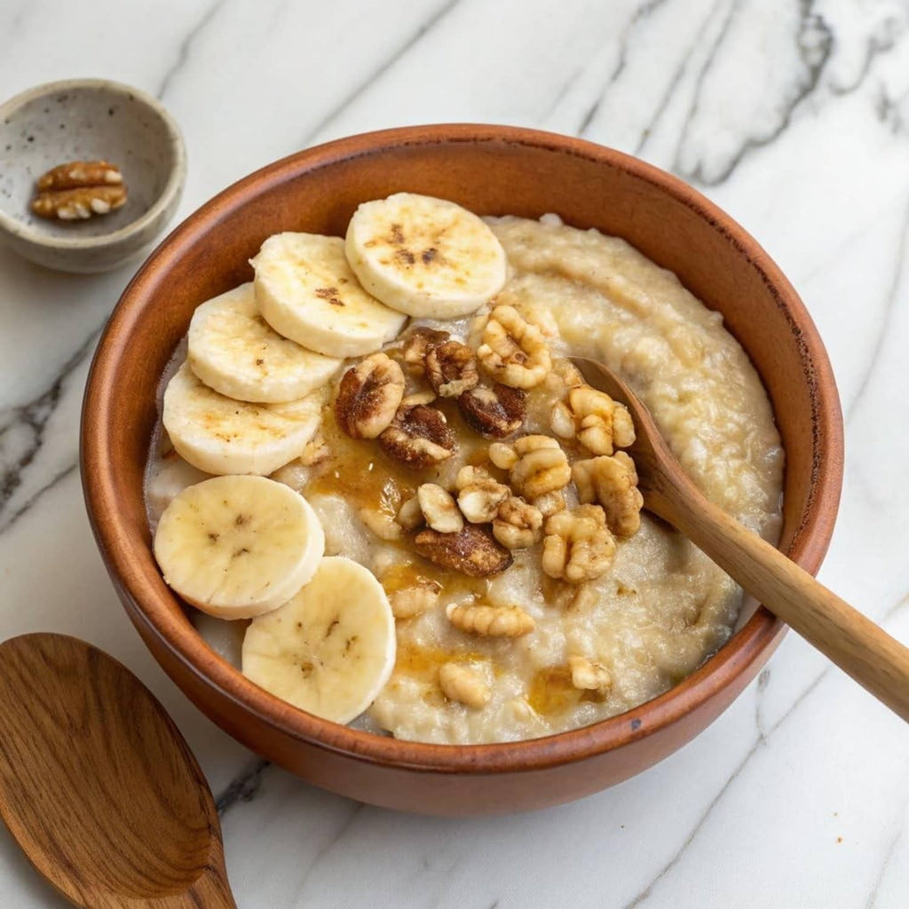 Bowl of oatmeal topped with banana slices, nuts, and walnuts
